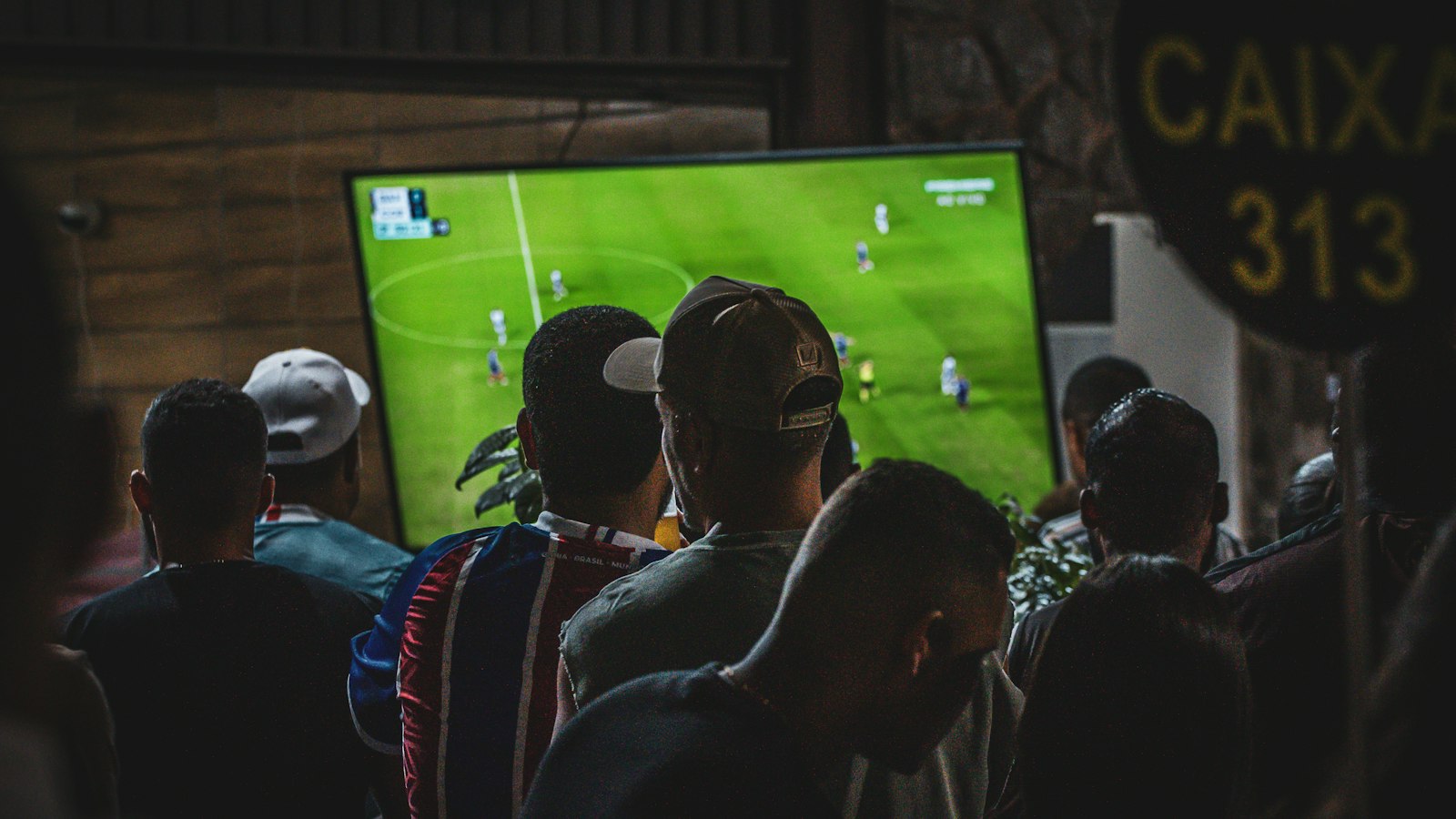 Groep mensen kijkt naar een voetbalwedstrijd op tv