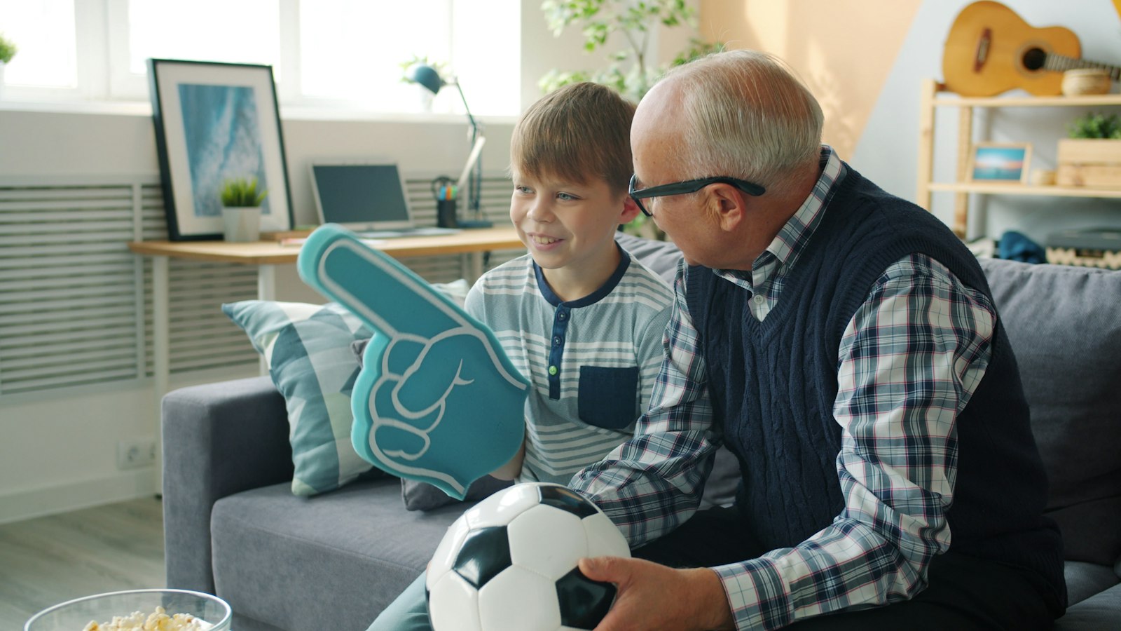 Bedstefar og barnebarn hepper på fodbold i tv