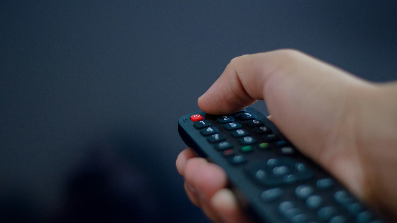 Hand met afstandsbediening voor de tv